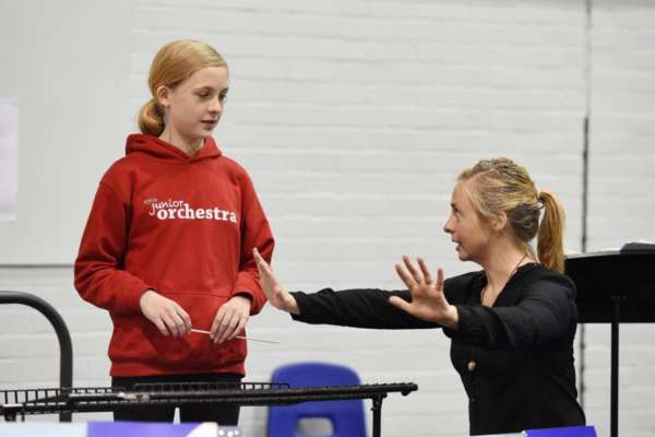 A member of NYOS Junior Orchestra receives a quick lesson from conductor Holly Mathieson